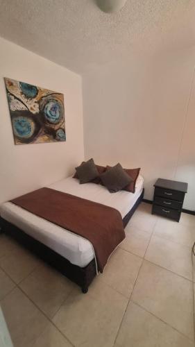 a bedroom with a bed and a painting on the wall at Alojamiento Santa Fe de Antioquia in Santa Fe de Antioquia