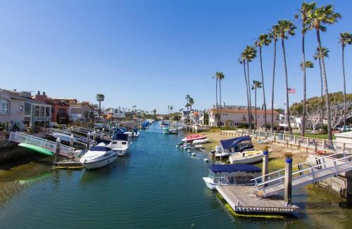 a group of boats docked in a river with palm trees at 209 38th St. B Condo in Newport Beach