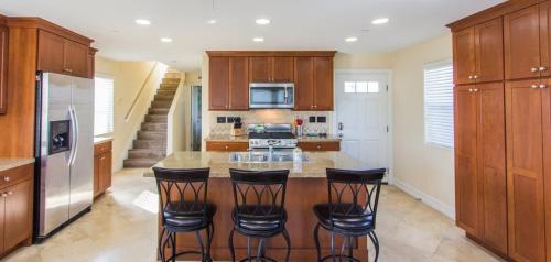 a kitchen with wooden cabinets and a island with bar stools at 209 38th St. B Condo in Newport Beach