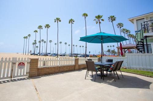 a table and chairs with a blue umbrella and the beach at 1005 E Balboa Unit A Lower #1 in Newport Beach