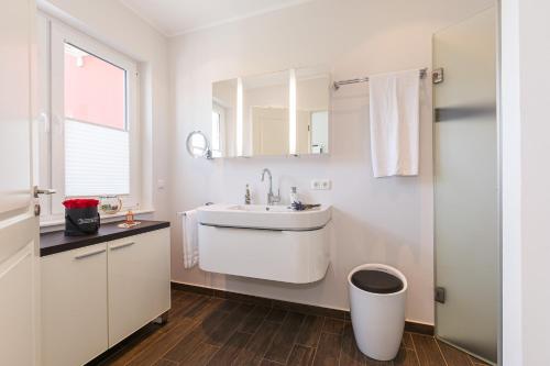 a white bathroom with a sink and a mirror at FeWo Sanfte Brise im EG mit Blick in die Natur in Göhren-Lebbin