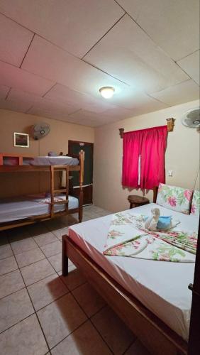 a bedroom with two beds and a red window at Ometepe House in Moyogalpa