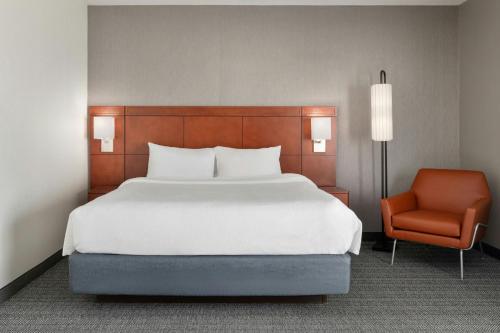 a bedroom with a large bed and a chair at Courtyard by Marriott Boston Norwood/Canton in Norwood