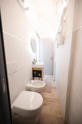 a white bathroom with a toilet and a sink at Chiarina rooms in Polignano a Mare