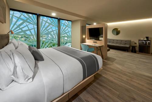 a hotel room with a large bed and a large window at City Express Plus by Marriott Merida in Mérida