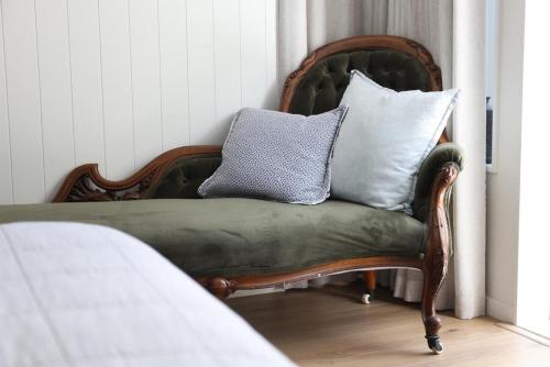 a chair with pillows on top of it in a room at Coastal Calm Papamoa in Tauranga