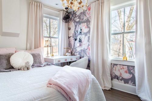 a bedroom with a bed and a chandelier and windows at THE LIBERTY HOUSE Of Old Town Designer Home in Alexandria