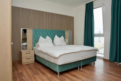 ein Schlafzimmer mit einem großen Bett mit grünem Kopfteil in der Unterkunft Mersa Hotel in Backnang