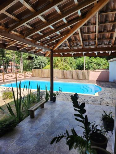 a large swimming pool with a wooden pergola at Chácara Pé da mata itajuba mg in Itajubá