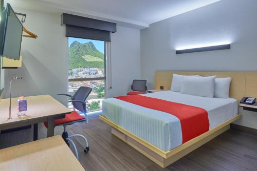 a hotel room with a bed and a desk and a window at City Express by Marriott Monterrey Lindavista in Monterrey