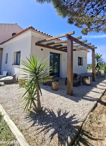a house with a wooden pergola in front of it at Meco Beach House in Sesimbra