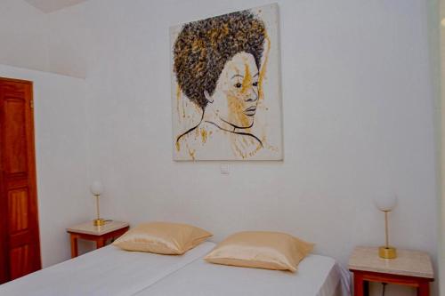 a painting of a woman on a wall with two beds at Casa 13 - Refúgio Salinas in Vila do Porto