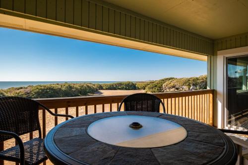 a table on a balcony with a view of the ocean at Castaway by Oak Island Accommodations in Caswell Beach