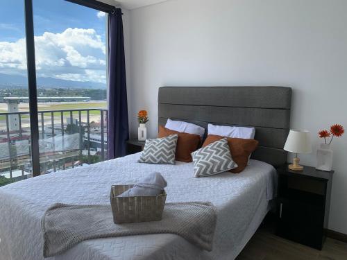 a bedroom with a bed with a large window at Inara 2 - Apartment with airport views - Zona 13 de la Ciudad de Guatemala in Estación Pamplona