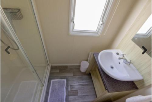 a bathroom with a sink and a shower and a window at Lyons Robinhood - 3 bedrooms in Rhyl