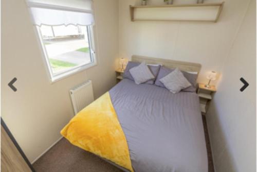 a bed in a small room with a window at Lyons Robinhood - 3 bedrooms in Rhyl