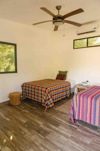 a bedroom with two beds and a ceiling fan at Alma Vita Punta Mango in Jucuarán