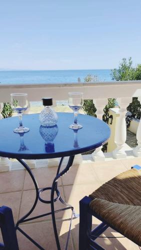 a blue table with wine glasses on a balcony at Pantelis Studio in Paralia Agias Foteinis