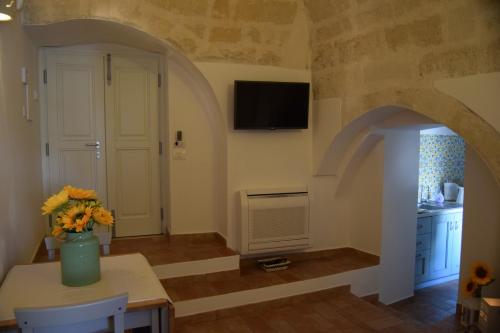 Una sala de estar con un jarrón de flores sobre una mesa. en Roseus La Casa Vacanze nei Sassi, en Matera