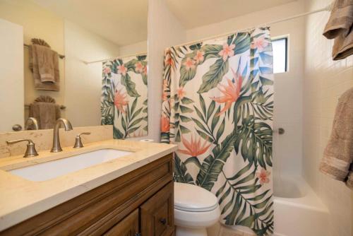 a bathroom with a sink and a toilet and a shower curtain at Hono Kai Resort B7 in Wailuku