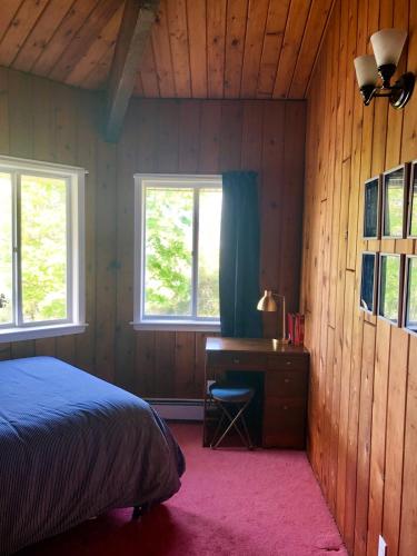 a bedroom with a bed and a desk and two windows at Waterfront Round House View in Oakdale