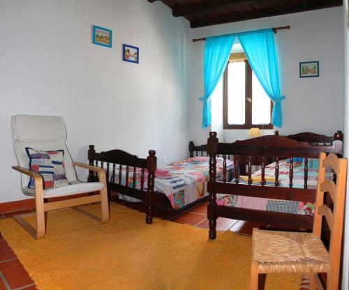 a bedroom with two beds and a chair and a window at Quinta do Pinhal in Constância