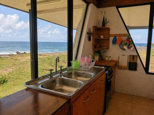 a kitchen with a sink and a view of the ocean at Cabañas & Hostal Tojika in Hanga Roa