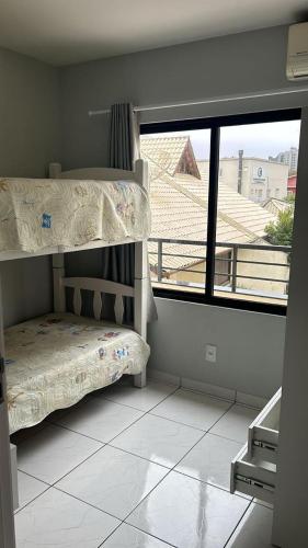 a bedroom with a bunk bed and a large window at Apto lateral mar in Porto Belo