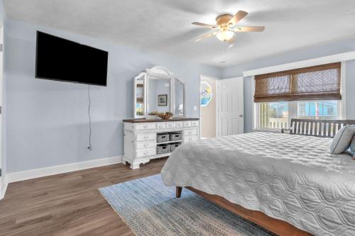 a bedroom with a bed and a flat screen tv at Clear For Take Off by Oak Island Accommodations in Caswell Beach