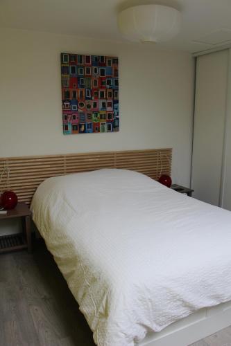 a white bed in a bedroom with a painting on the wall at L' Atelier de la Monnaie in Crémieu