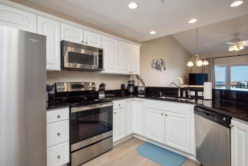 a kitchen with white cabinets and stainless steel appliances at Clearly Hooked by Oak Island Accommodations in Oak Island