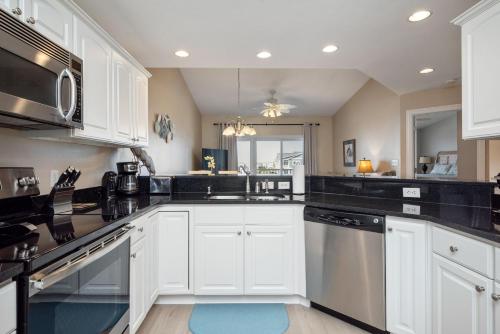 a kitchen with white cabinets and black counter tops at Clearly Hooked by Oak Island Accommodations in Oak Island