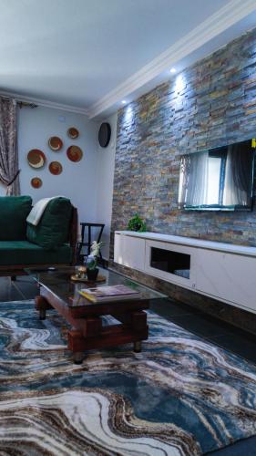 a living room with a green couch and a brick wall at The apartment Bwebajja 3 in Namulanda