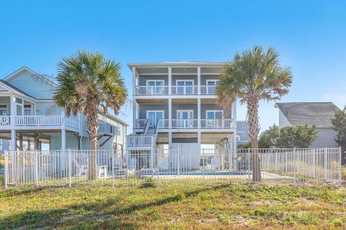 a large house with palm trees in front of it at Conch Out by Oak Island Accommodations in Oak Island