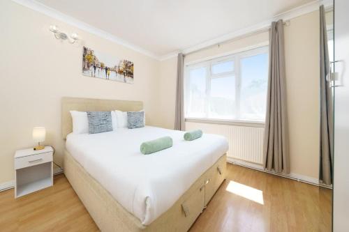 a bedroom with a large white bed and a window at 2BR Apartment near Heathrow Airport in Wallington