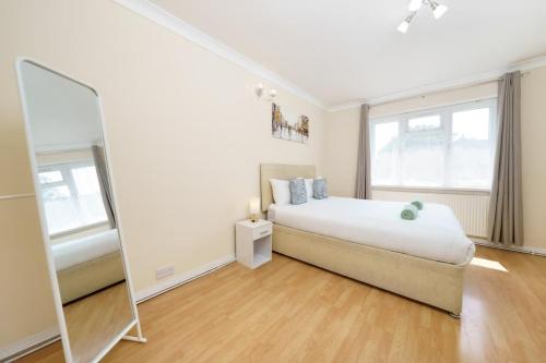 a white bedroom with a bed and a mirror at 2BR Apartment near Heathrow Airport in Wallington