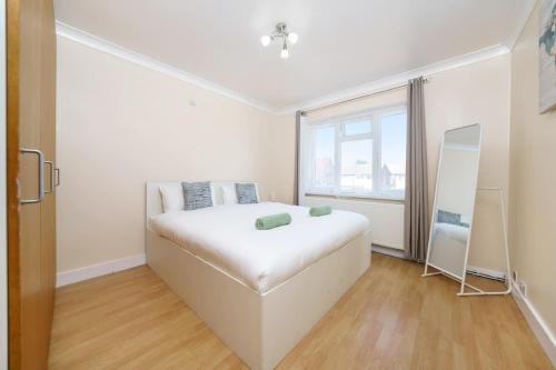 a white bedroom with a large white bed and a window at 2BR Apartment near Heathrow Airport in Wallington