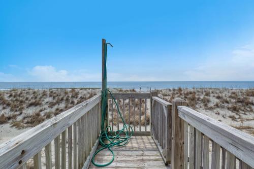 a wooden boardwalk leading to the beach with a green water hose at Divine Intervention by Oak Island Accommodations in Oak Island