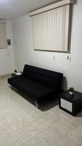 a black couch in a living room with two tables at Casa Vivanco apartment #5 in Ensenada