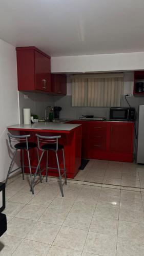 a kitchen with red cabinets and a table and chairs at Casa Vivanco apartment #5 in Ensenada