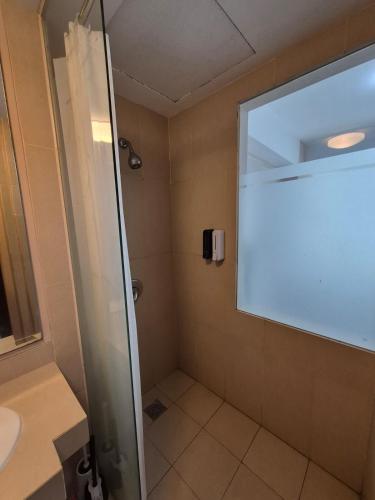 a shower with a glass door in a bathroom at Cozy 1BR UResidence 2 by REJA Essentials in Klapadua