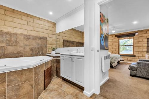 a bathroom with a tub and a sink and a bedroom at Route 86 Bright in Bright