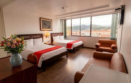 una camera d'albergo con due letti e un divano di Hotel Cordero a Cuenca