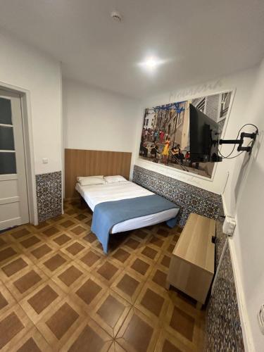 a bedroom with a bed and a tv on a wall at BrotherStay Rooms lusotile in Lisbon