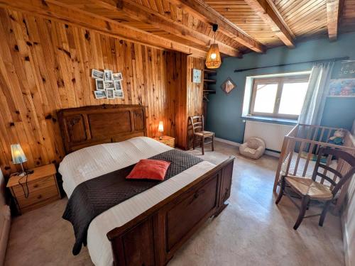 a bedroom with a large bed in a room with wooden walls at Gîte paisible dans ancienne ferme comtoise avec animaux acceptés - FR-1-583-416 in Saint-Bresson