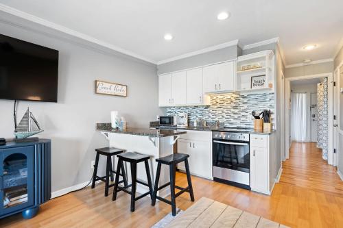 a kitchen with white cabinets and a bar with stools at New Listing - Spring Discounts Beach View Condo in Hilton Head Island