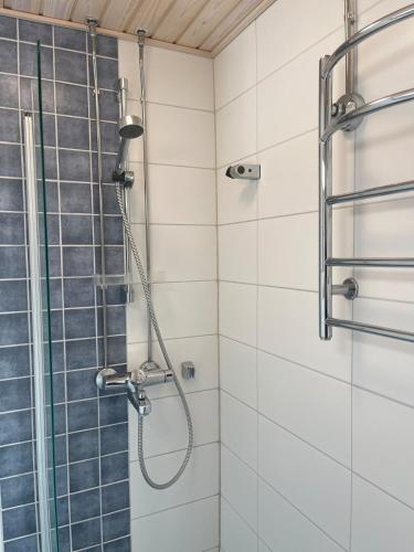 a shower in a bathroom with white tiles at Apartments Maaherrankatu in Kuopio