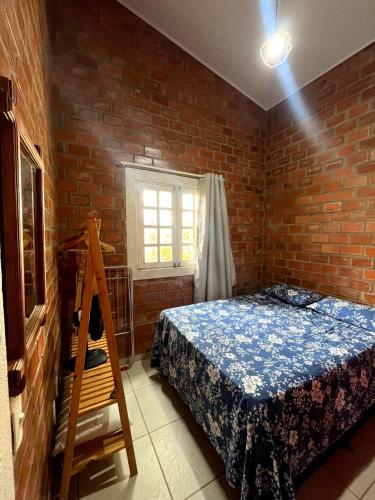 a bedroom with a bed and a brick wall at Chalés serra negra in Bezerros