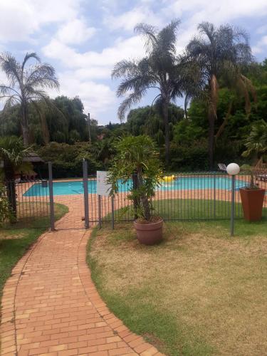 a fence with palm trees and a swimming pool at Premium Executive Room in Sandton