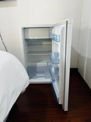 an empty refrigerator with its door open next to a bed at Premium Executive Room in Sandton